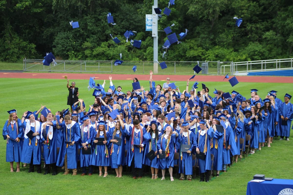 Valley Central High School graduating class celebrating by tossing their caps in the air